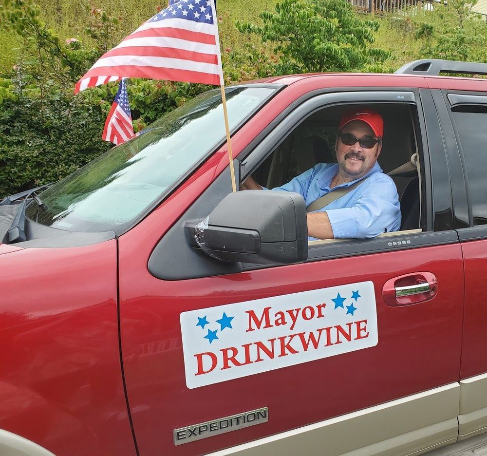 Mayor Sean Drinkwine waves from his red Ford Expedition, decorated with American flags and a Mayor Drinkwine sign, during an Estacada parade